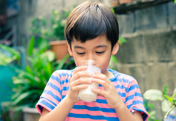 Littl boy drinking milk in the park vintage color style