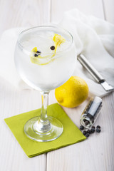 Gin tonic en copa de balón con twist de limón y bayas de enebro