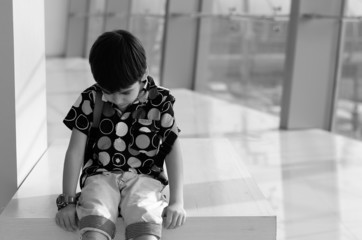 Little boy sitting on the chair with sadness
