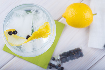 Gin tonic en copa de balón con twist de limón y bayas de enebro