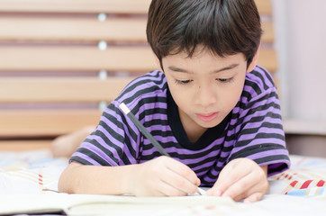 Little boy writing diary on the bed