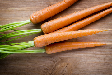 Fresh carrots on the wooden background.
