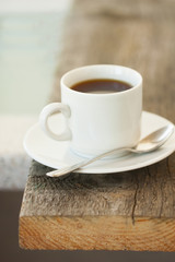 cup of  coffee on the edge of a wooden table