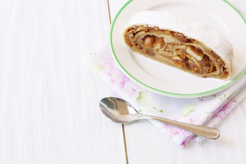 a piece of apple strudel on a plate on a light background