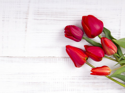 red tulip bouquet on white wooden background