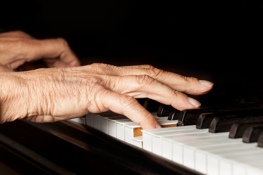 Old person's hands playing piano. Active senior close up
