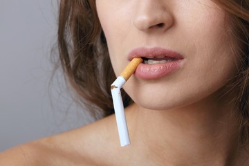 Junge Frau mit durchgebrochener Zigarette im Mund