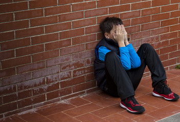 bambino disperato si copre il volto