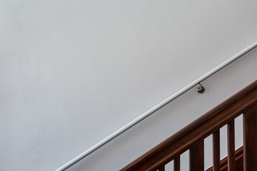 Wooden staircase in front of white wall with handrail