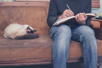 Man sitting on sofa writing in notebook