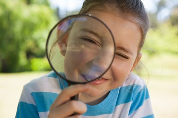Cute little girl looking through magnifying glass