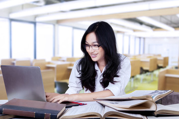 Obraz na płótnie Canvas Attractive teenage schoolgirl typing on laptop