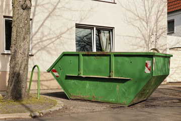 Fototapeta na wymiar Ein grüner Container für Abfall steht vor einem Wohnhaus