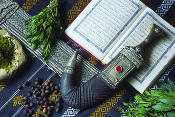 Quran, janbiya, henna and coffee on table