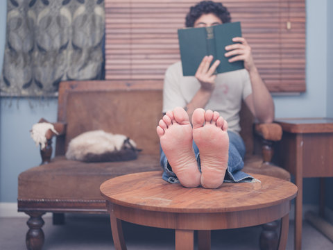 Barefoot man reading at home