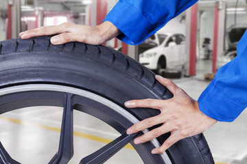Mechanic hands pushing tire at workshop