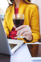 Woman with red wine tablet and laptop in street cafe