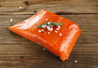 Salmon steak with herbs on wooden background.