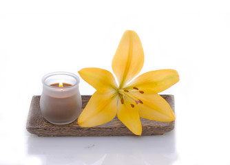 Fototapeta na wymiar yellow lily and candle in wooden bowl