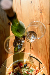 Wineglasses green bottle of wine and fresh baked pizza