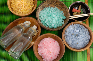 Set of Colorful salt in wooden bowl with massage oil on green mat