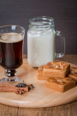 Glass cup of coffee and cinnamon stick with almond cookies