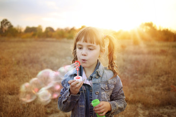The girl in pigtails lets soap bubbles