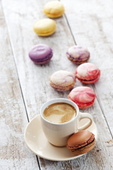 Viele bunte Macaron mit Kaffeetasse, heller Holzuntergrund