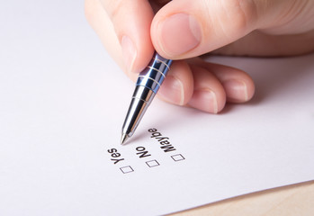 close up of female hand filling survey with yes, no, maybe answe