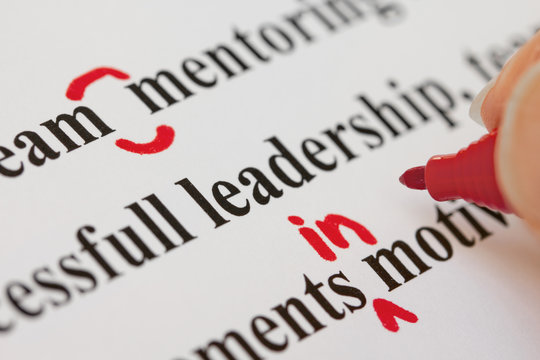 Hand with Red Pen Proofreading Text Closeup