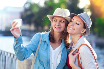 Obraz premium Two happy beautiful girls taken picture of themself in the city