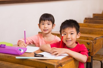 Cute pupils smiling at camera in classroom