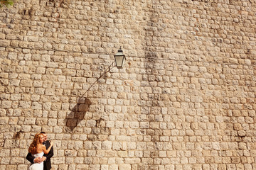 groom and bride in front of a big brick wall