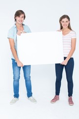 Hipster couple holding poster and smiling at camera
