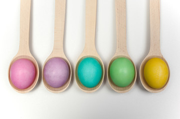row of easter eggs on wooden spoons isolated white
