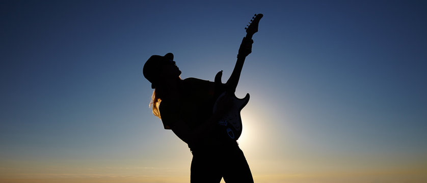 Silhouette of female busker in front of sunrise