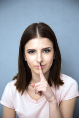 Naklejka premium Portrait of a cute woman with finger over lips