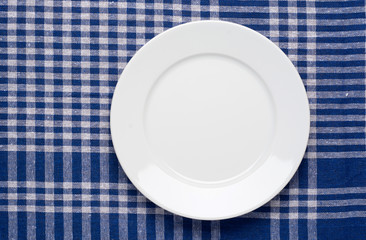 White classic plate on blue checkered tablecloth.