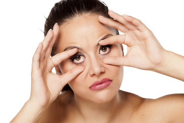 Fototapeta premium funny young woman holding her eyes open with her fingers