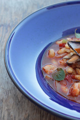 Beans and chorizo cooked with seafood on a blue plate.