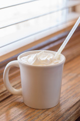 Creamy cappuccino on wooden table near window