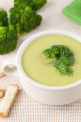 Healthy green broccoli soup with croutons in a white dish