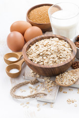 oat flakes and ingredients on a white wooden table, vertical