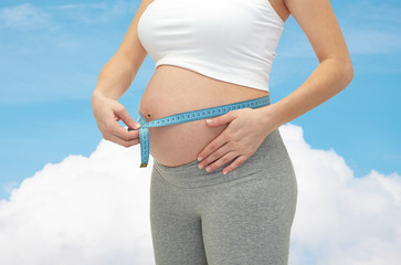 close up of pregnant woman measuring her tummy