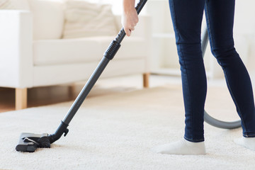 close up of woman legs with vacuum cleaner at home