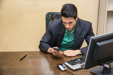 Handsome young businessman dialing on cell phone or typing text