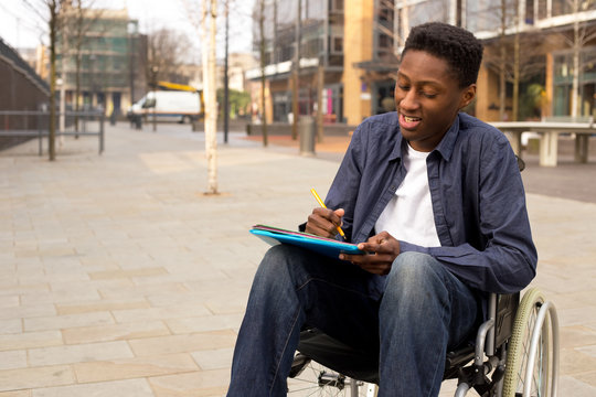 young man in a wheelchair writing a letter
