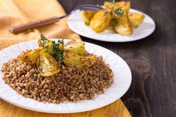 Buckwheat porridge with baked onions on a wooden table