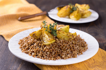 Buckwheat porridge with baked onions on a wooden table