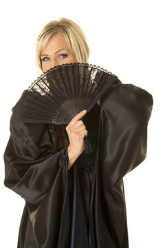 woman in black cloak smile behind fan